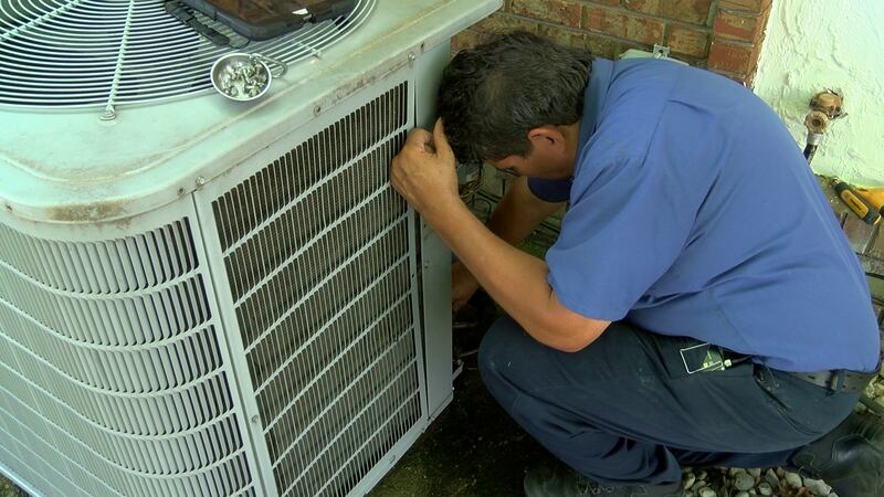 Marcos Barrera works to clean an air conditioning unit.